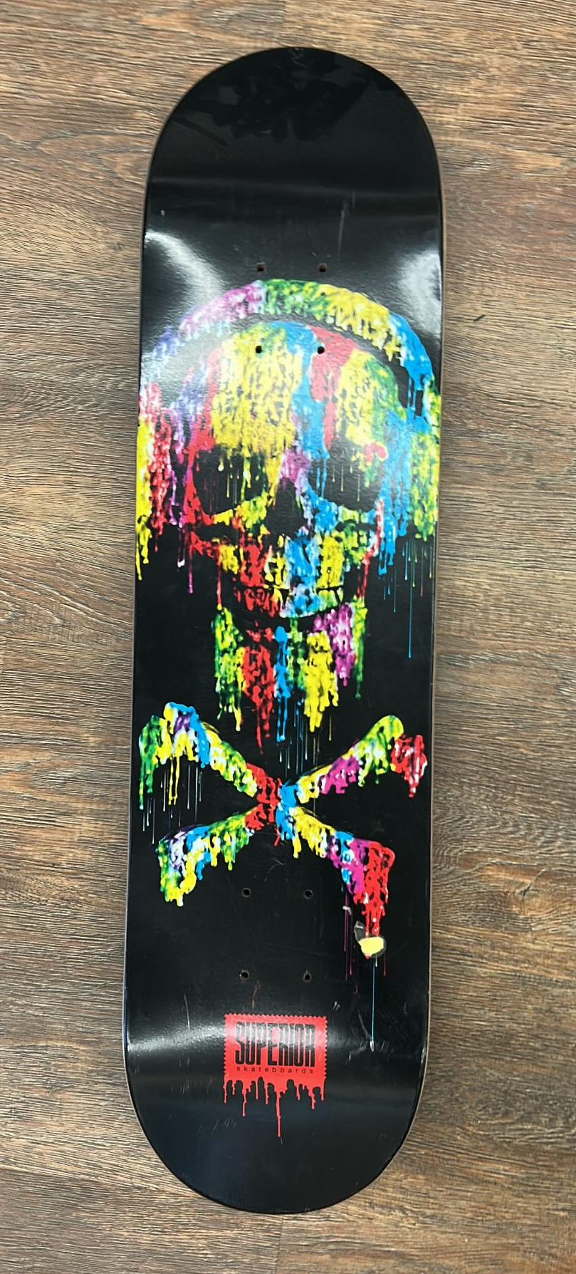 Superior skateboard deck featuring a colorful, dripping skull and crossbones graphic